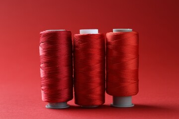 Spools of bright sewing threads on red background