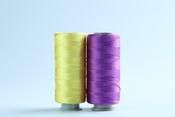 Spools of colorful sewing threads on light background