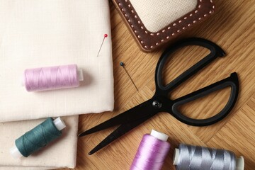 Sewing threads and other supplies on wooden table, flat lay