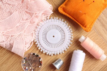 Sewing threads and other supplies on wooden table, flat lay