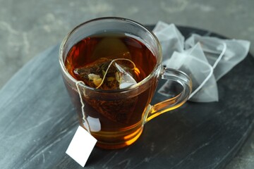 Tea bag in glass cup with hot drink on gray table, closeup