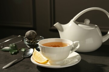 Refreshing green tea in cup and slice of lemon on dark textured table