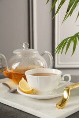 Refreshing green tea, spoon and slice of lemon on dark textured table