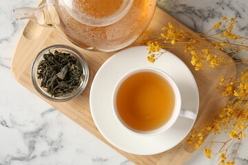 Refreshing green tea and dry leaves on white marble table, flat lay