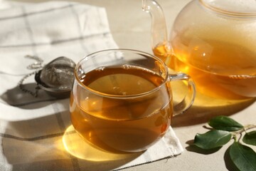 Refreshing green tea, strainer and leaves on textured table, closeup