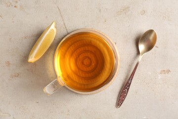 Refreshing green tea, slice of lemon and spoon on light textured table, flat lay