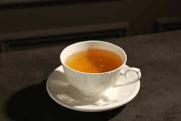 Refreshing green tea in cup on dark textured table, closeup