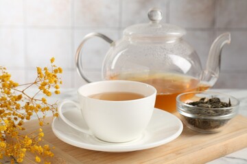 Refreshing green tea and dry leaves on white table, closeup