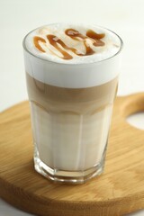 Tasty latte macchiato in glass on white wooden table, closeup