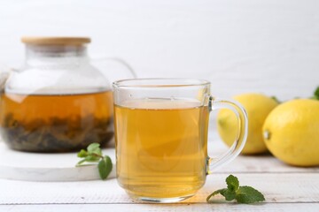 Aromatic mint tea with lemons and fresh leaves on white wooden table, closeup