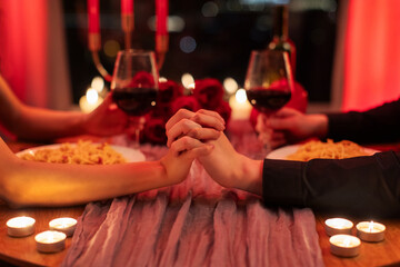 Romance and love. Closeup of couple holding hands, sitting at table in restaurant, drinking wine and eating pasta, having romantic date