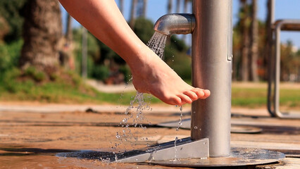 Beach shower. Girls wash their feet from sand with tap water near the beach. People wash their feet when leaving the beach. Women wash their feet close-up. Beach shower near the sea