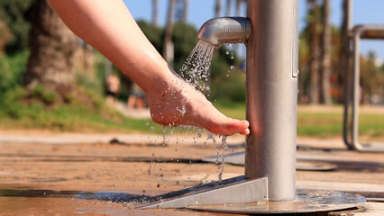 Beach shower. Girls wash their feet from sand with tap water near the beach. People wash their feet when leaving the beach. Women wash their feet close-up. Beach shower near the sea