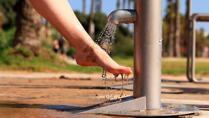 Beach shower. Girls wash their feet from sand with tap water near the beach. People wash their feet when leaving the beach. Women wash their feet close-up. Beach shower near the sea