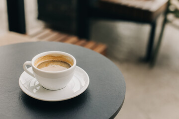 Cup of black coffee on a table in a street cafe.