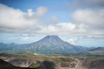Fototapeta premium Vilyuchinsky Volcano, Kamchatka region. A breathtaking and stunning view of a magnificent volcano set amidst dramatic clouds and vibrant, lush landscapes