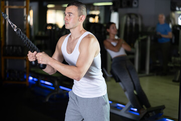 Man in sportswear training on rope loop simulator in gym