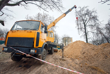 Crane truck working on construction site in city park, replacing and repairing utility pipelines in...