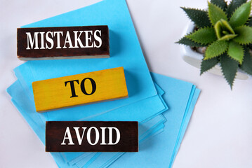 MISTAKES TO AVOID - words on wooden blocks on a light background with a cactus