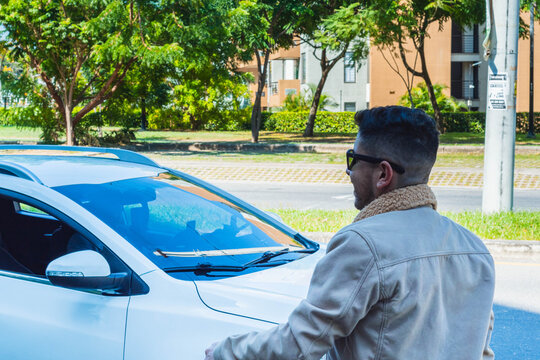 A traveler man standing, man wearing a jacket is happy because his car arrived, smiling man in front of a white vehicle