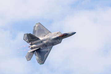 Close top view of a F-22 Raptor in beautiful light in a turn, with afterburners on