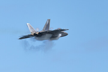 Very unusual close view of a F-22 Raptor at very high speed, with condensation cone (“singularity”) around the plane