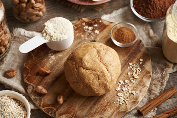 Ball of raw dough made of whey protein, ground oat flakes, maple syrup and nut butter - ingredient...