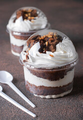 Takeaway dessert of chocolate sponge cake, whipped cream and nuts