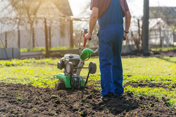 A man engaged in agriculture plows the soil with a cultivator for further planting of vegetables