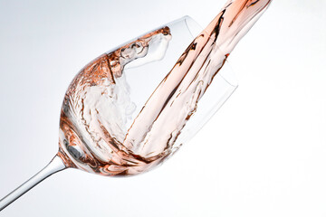 Fototapeta premium Pouring rose wine into glass on white background