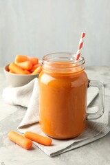 Fresh carrot juice in mason jar and vegetables on gray textured table