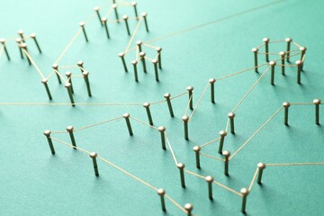 Network connection. Nails linked together by thread on green background, closeup
