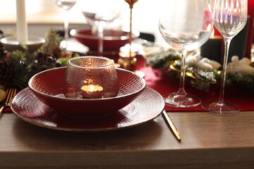 Christmas place setting with festive decor on wooden table in room, closeup