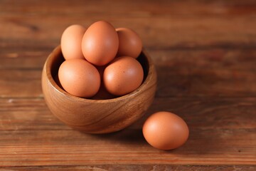 Fresh eggs in bowl on wooden table, closeup