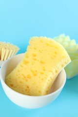 Sponges and bowl on light blue background, closeup