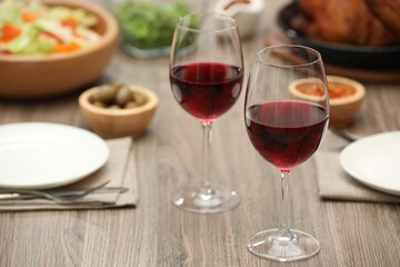 Red wine and delicious dinner served on wooden table, closeup. Space for text