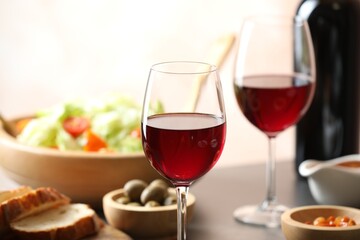 Red wine and delicious dinner served on table, closeup