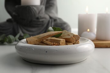 Palo santo sticks and eucalyptus leaves on white table, closeup
