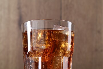 Sweet soda water with ice cubes in glass on blurred background, closeup
