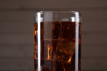 Sweet soda water with ice cubes in glass on blurred background, closeup