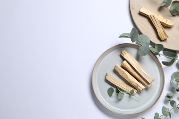 Palo santo sticks and eucalyptus branches on white background, flat lay. Space for text