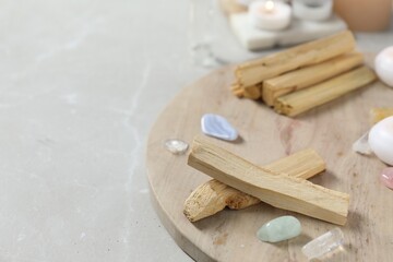 Palo santo sticks and gemstones on light table. Space for text