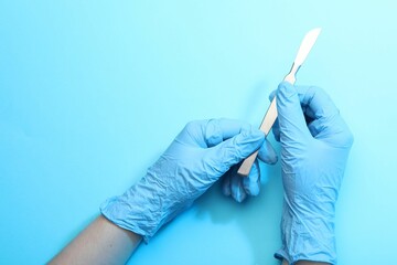 Doctor with surgical scalpel on light blue background, top view. Space for text