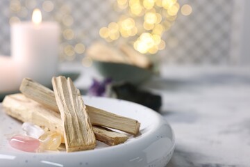 Palo santo sticks, gemstones and burning candle on light grey table, closeup. Space for text