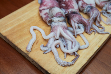 Fresh raw squids  on wooden chopping board, background Seafood squid, ready to be cut and cooked. top view and copy space for your text