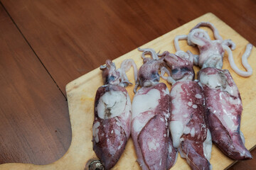 Fresh raw squids  on wooden chopping board, background Seafood squid, ready to be cut and cooked. top view and copy space for your text