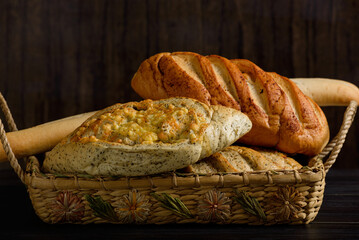 Basket with rustic spiced breads on wooden table. Dark background