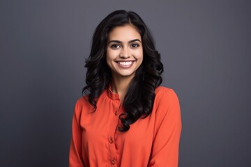 Fototapeta premium Portrait of a young latin woman with pleasant smile, isolated on grey wall with copy space. Cheerful hispanic woman on grey background with copy space.