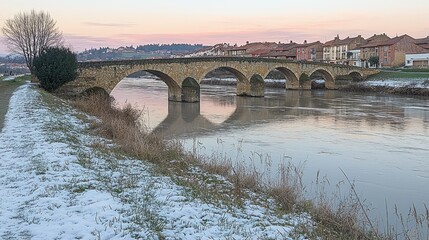 Fototapeta premium Stone Arch Bridge Spanning River in Winter Sunset