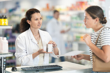 Female pharmacist offering medicine for sore throat to customer